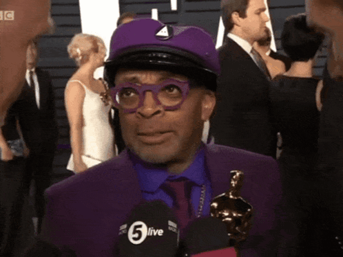 Man in Purple Suit Talking Into 5live Microphone