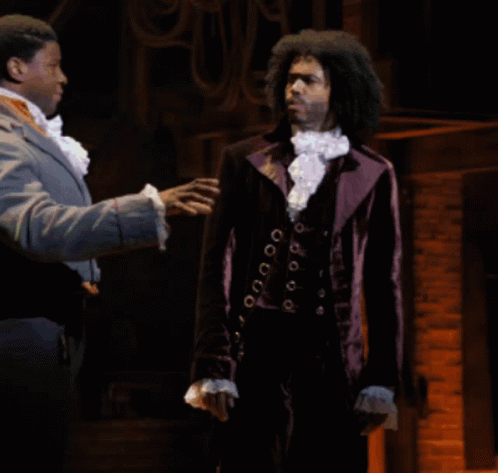 Man in Purple Suit Talking to Another Man