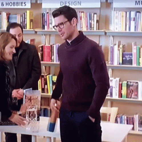 Man in Purple Sweater and Glasses at Design Sign