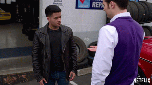 Man In Purple Vest Talking To Man In Front Of Certified Mechanic Sign GIF