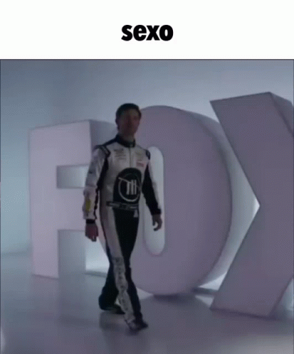 Man In Race Suit Walking Past Fox Sign GIF