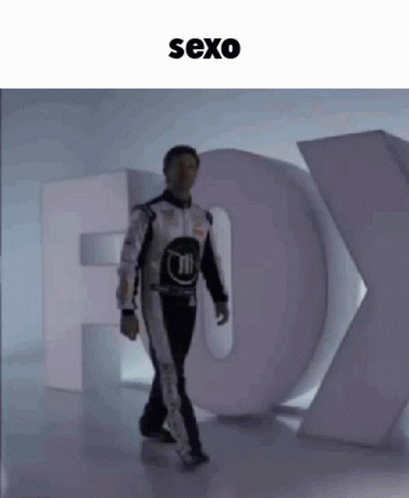 Man in Race Suit Walking Past Fox Sign