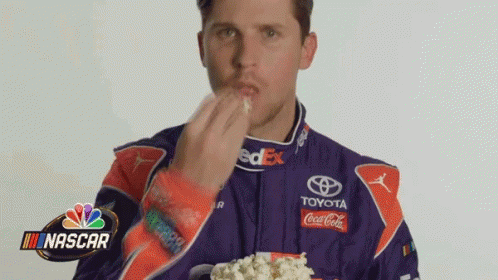 Man in Racing Suit Eating Popcorn from Cup