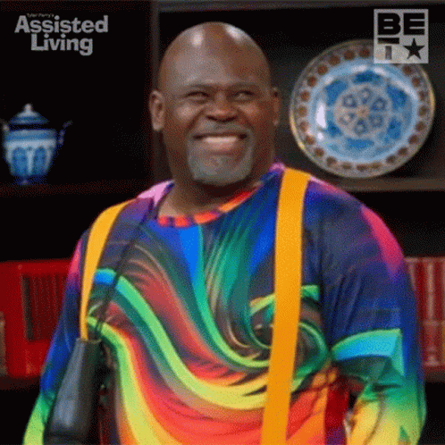 Man in Rainbow Shirt and Suspenders Smiling With Plates
