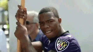 Man in Ravens Shirt Holding Stick