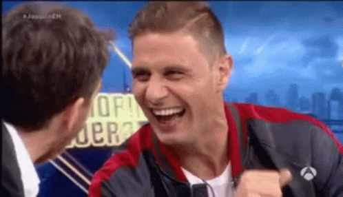 Man in Red and Black Jacket Laughing With Suit Man