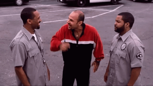 Man In Red And Black Jacket Talking To Guards GIF