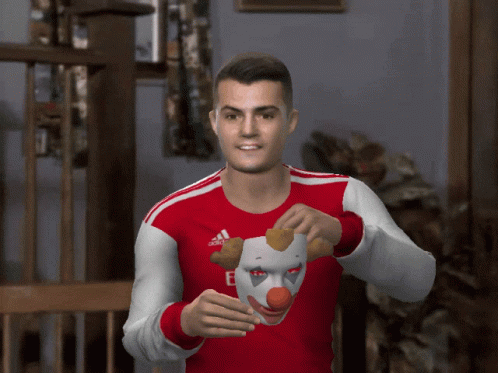 Man in Red and White Adidas Shirt Holding Clown Mask