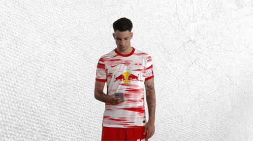 Man in Red and White Shirt With Red Bull Looking at Phone
