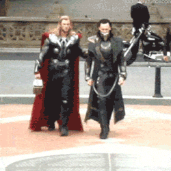 Man in Red Cape Walking Next to Man in Black Suit