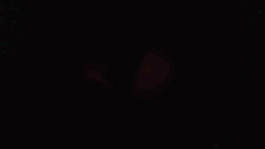 Man in Red Coat Staring at Camera in Dark Room
