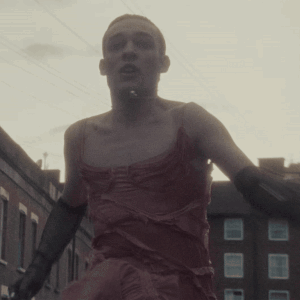 Man In Red Dress And Black Gloves Walking GIF