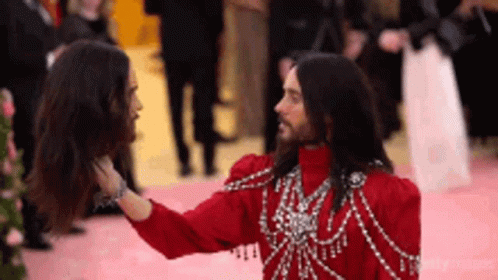Man in Red Dress Touching Another Man's Head