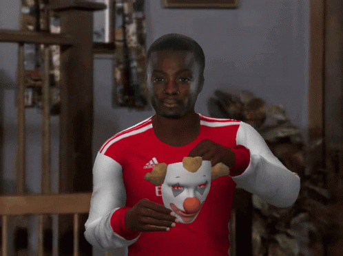 Man In Red Emirates Sweatshirt Holding Clown Mask GIF