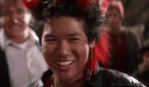 Man in Red Feathered Headdress Smiling in Crowd