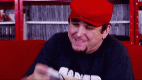 Man in Red Hat and Black Shirt Smiling Holding Remote
