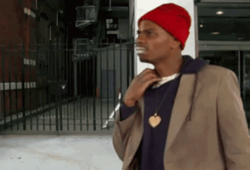 Man in Red Hat and Brown Jacket by Fence