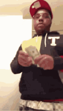 Man In Red Hat And Glasses Holding Money GIF