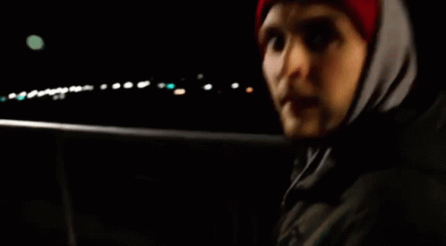 Man in Red Hat and Hooded Jacket in Dark