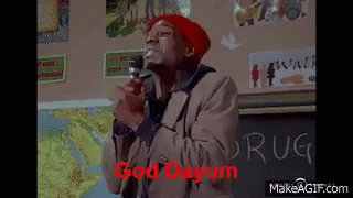 Man In Red Hat Holding Microphone In Front Of Chalkboard Saying Drug GIF