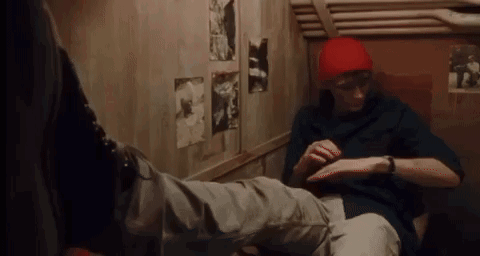 Man in Red Hat Sitting Next to Another Man