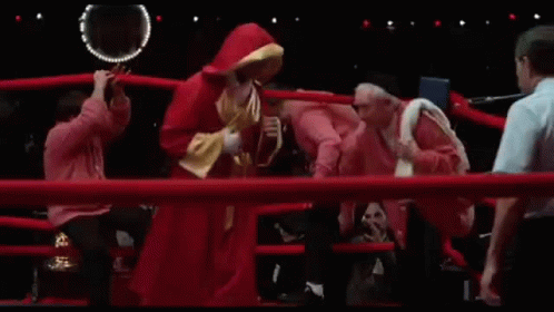 Man in Red Hoodie and Referee in Boxing Ring