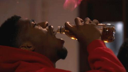 Man in Red Hoodie Drinking From Bottle With Flames