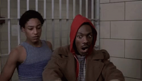 Man in Red Hoodie Sitting in Jail Cell With Another Man