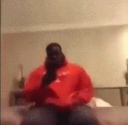 Man in Red Hoodie Talking on Phone on Bed