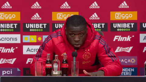 Man in Red Jacket at Table With Coca Cola and Microphone