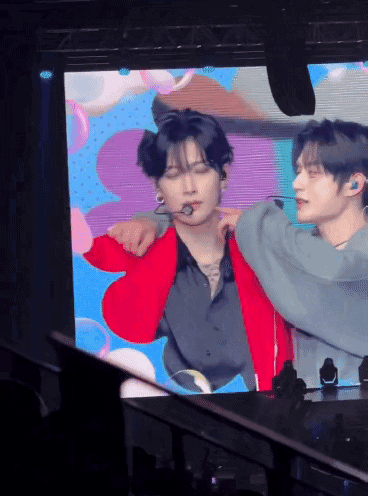 Man in Red Jacket Being Held by Another Man