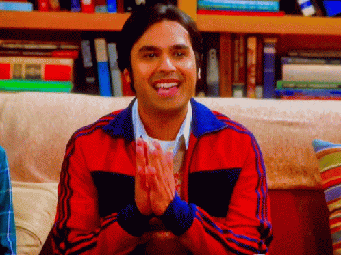 Man in Red Jacket Clapping Hands in Front of Bookshelf