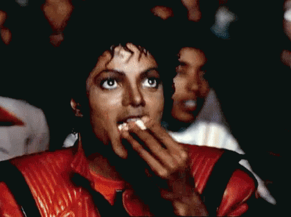 Man in Red Jacket Eating Popcorn in Crowd