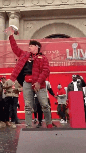 Man In Red Jacket Holding Trophy On Stage GIF