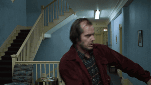 Man In Red Jacket In Hallway Near Stairs GIF