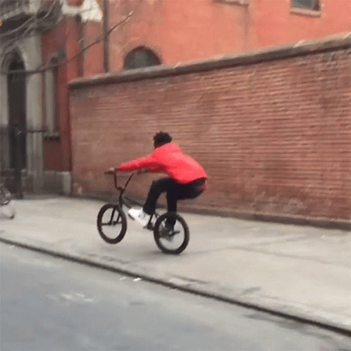 Man in Red Jacket Riding Bike Down Street