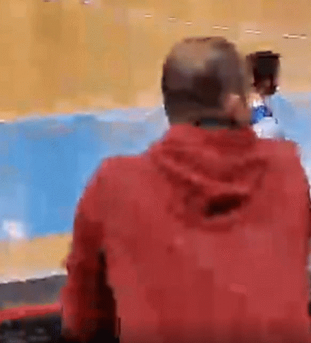 Man in Red Jacket Sitting Against Blue Wall