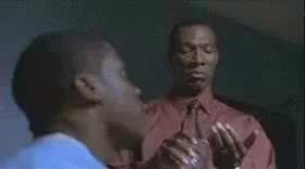 Man In Red Jacket Standing By Woman In Blue Shirt At Desk GIF