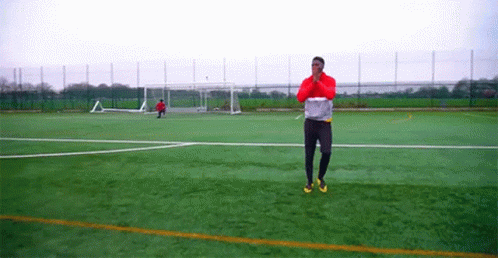 Man in Red Jacket Standing on Soccer Field with Goal