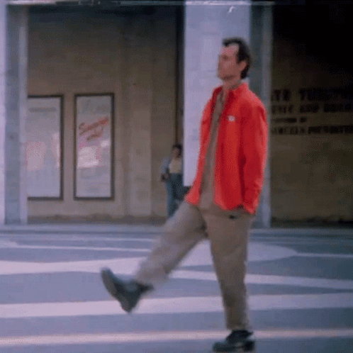 Man In Red Jacket Walking Down Street GIF