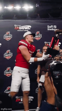 Man in Red Jersey Holding Trophy in Front of Bowl Sign