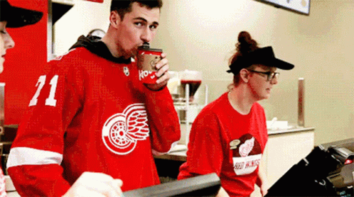 Man in Red Jersey Number 71 Drinking Coffee