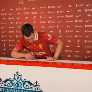 Man in Red Liverpool Jersey Signing Paper