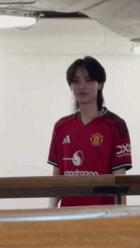 Man In Red Manchester United Jersey Standing By Table GIF
