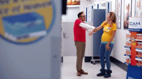 Man In Red Next To Pregnant Woman In Yellow GIF