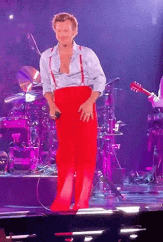 Man in Red Pants and Suspenders Standing on Stage