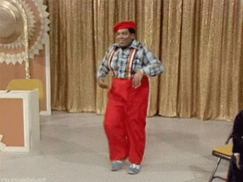 Man in Red Pants Dancing on Stage in Front of Gold Curtain
