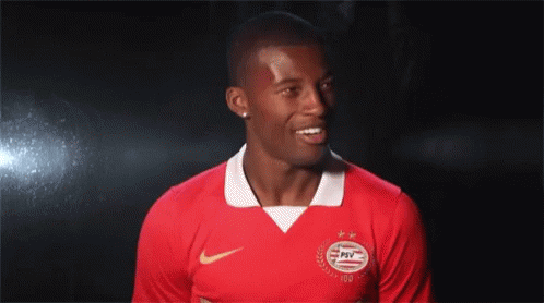 Man in Red PSV Jersey Smiling in Dark