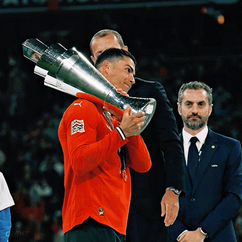 Man in Red Puma Shirt Holding Large Trophy