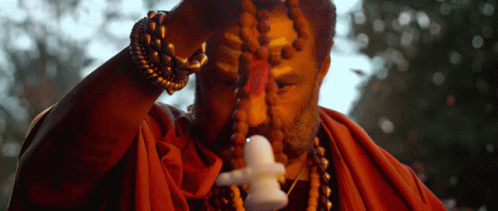 Man In Red Robe Holding Small Statue GIF